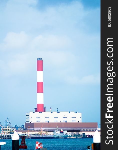 Industrial chimney in red and white color around a habor area.