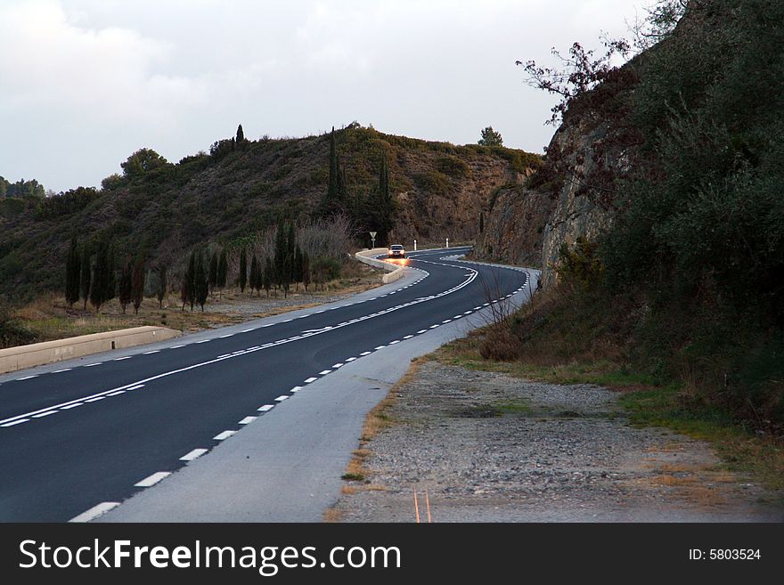 Road curves with a car at sunrise