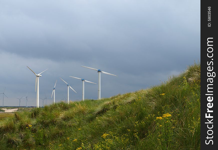 Wind turbines along the coast harvesting energy on a stormy day. Wind turbines along the coast harvesting energy on a stormy day