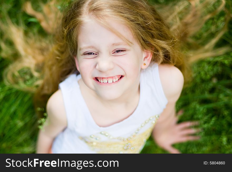 Smiling cute little girl outside in green grass