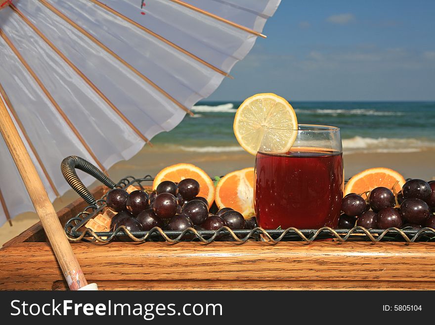 Glass of vine juice with the lobule of lemon and fruits  on a background a sea-piece
