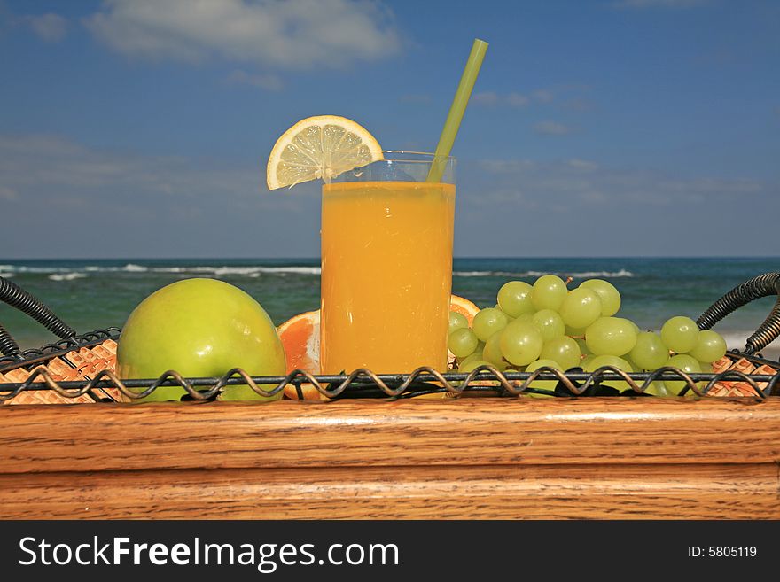 Glass of orange juice in surroundings fresh fruits on a background a sea-piece