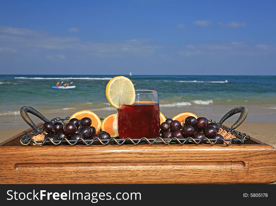 Glass of vine juice with the lobule of lemon and fruits  on a background a sea-piece