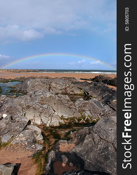 A rocky beach on a warm wet day with a calm sea and a rainbow after a shower an ideal place to have a walk in ireland. A rocky beach on a warm wet day with a calm sea and a rainbow after a shower an ideal place to have a walk in ireland