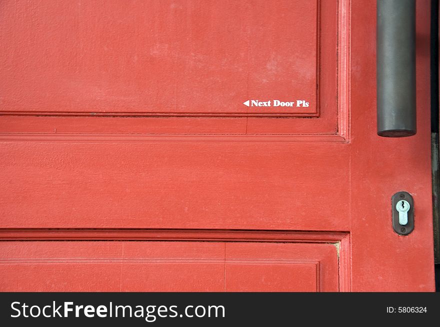 A door painted with words that says Next Door Please.