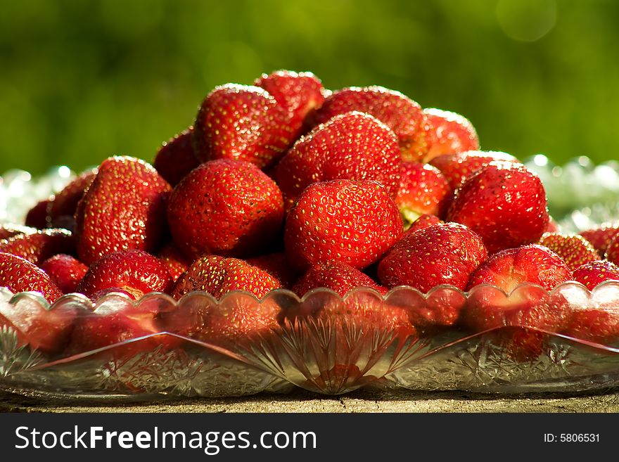 Bowl of sweet strawberries over a green summer background. Bowl of sweet strawberries over a green summer background