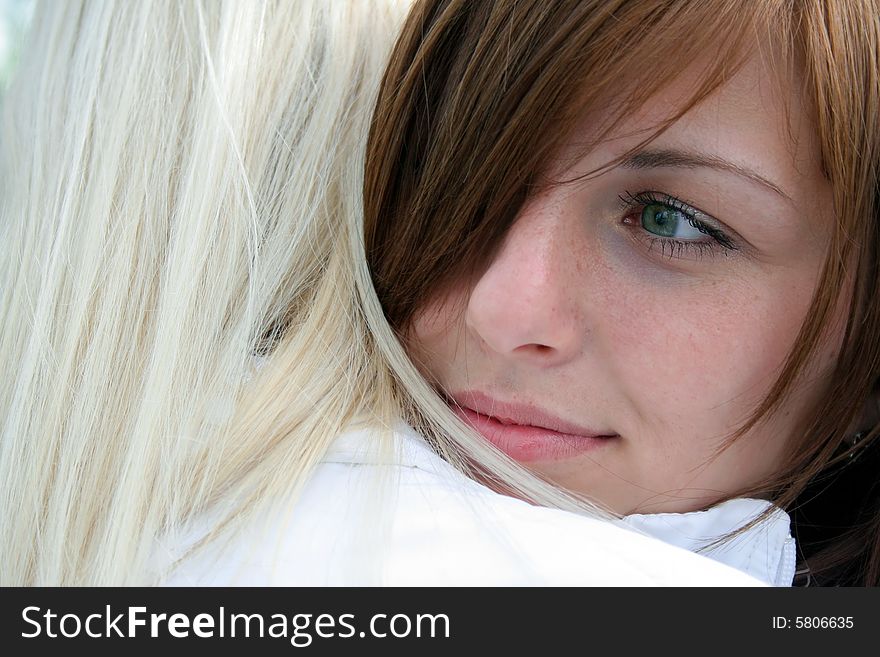 Young beautiful woman with a big green eyes put her head on the shoulder of the other, and looking somewhere thoughtfully