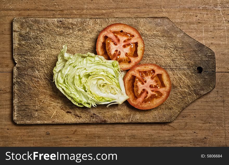 Cut tomatoes and lettuce on cutting table.