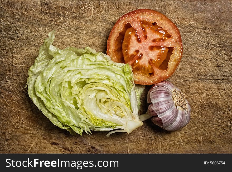 Fresh tomato, lettuce and garlic on wooden table.