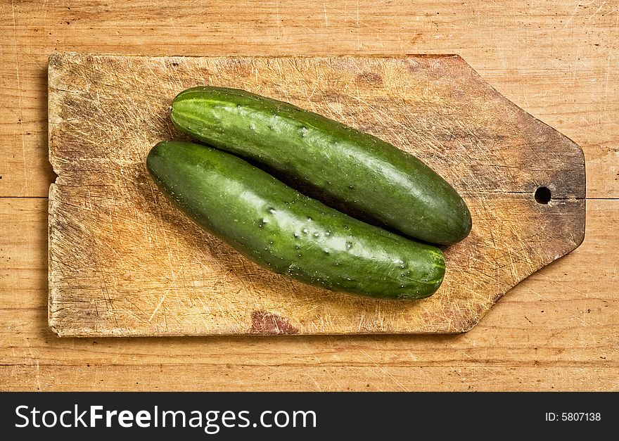 Two cucumbers on a wooden kitchen table.