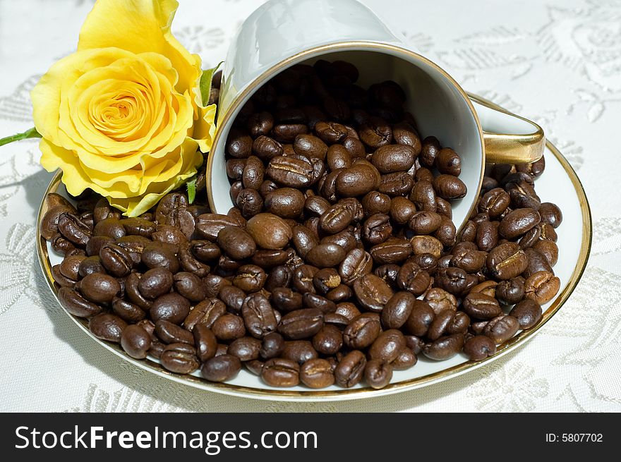 Coffee beans in fallen white retro cup with yellow rose. Coffee beans in fallen white retro cup with yellow rose