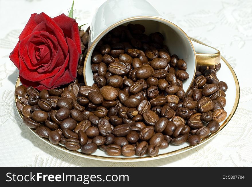 Coffee beans in fallen white retro cup with red rose. Coffee beans in fallen white retro cup with red rose