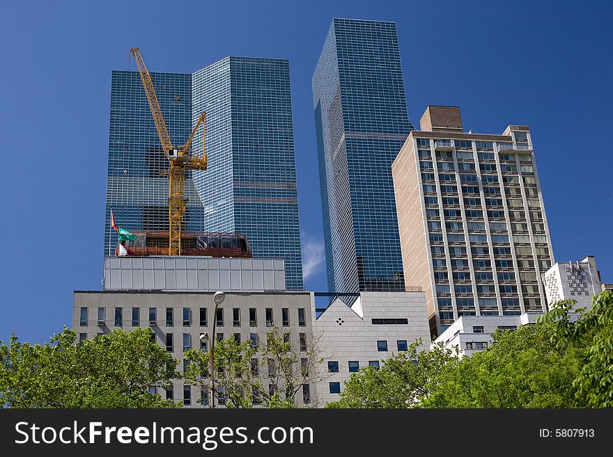 A group of skyscrapers with a crane indicating construction work. A group of skyscrapers with a crane indicating construction work