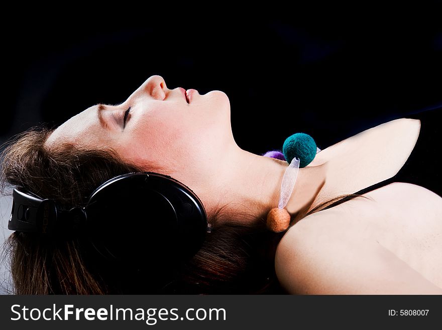 The beautiful woman listens to music through headphones. The beautiful woman listens to music through headphones