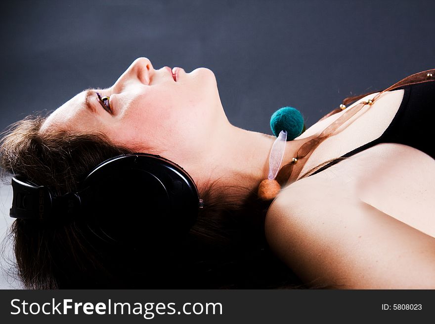 The beautiful woman listens to music through headphones. The beautiful woman listens to music through headphones