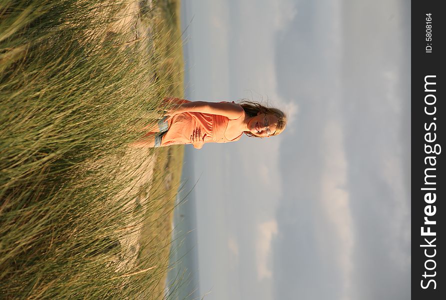 Happy girl on the dune in sunset light, happy holidays in France on the Atlantic ocean shore. Happy girl on the dune in sunset light, happy holidays in France on the Atlantic ocean shore