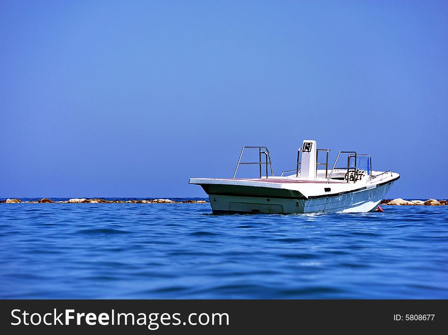 Boat on the Mediterranean sea against a background of rocks and blue sky