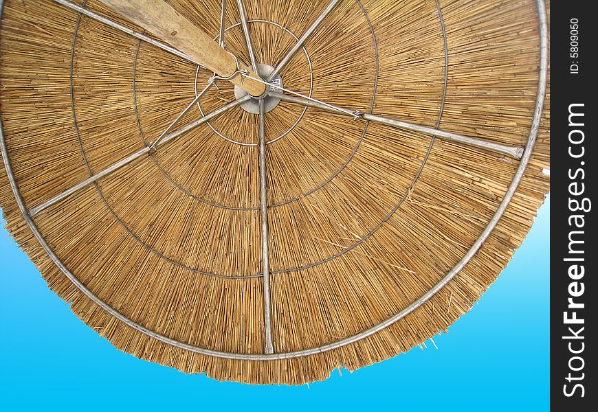 Detail of grass beach umbrella against blue sky