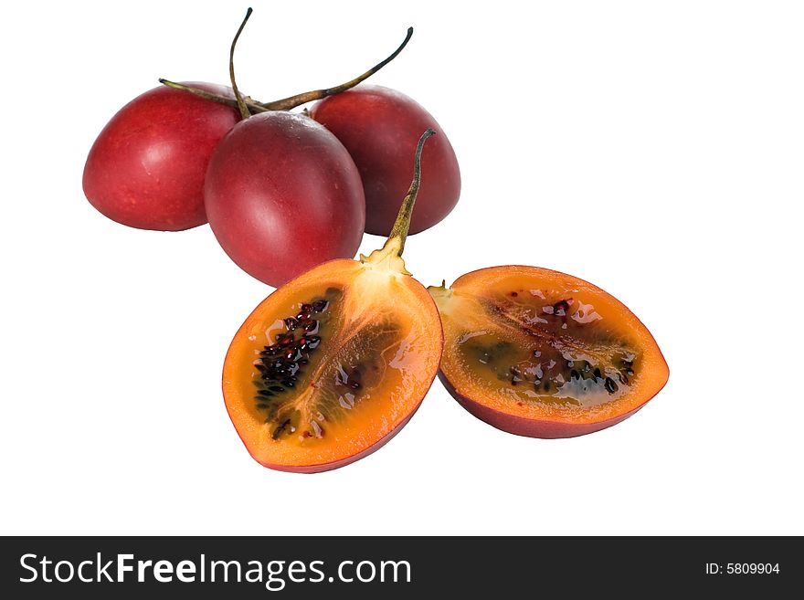 Whole and halved fresh Tamarillo fruit showing its deep red seeds and tangy sweet flesh. Whole and halved fresh Tamarillo fruit showing its deep red seeds and tangy sweet flesh