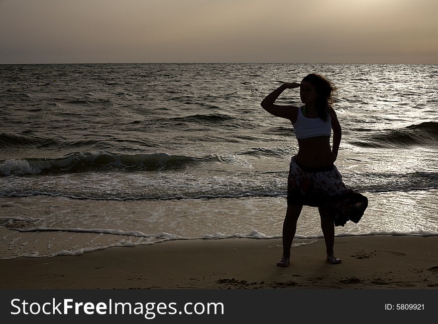 Silhouette of girl at dawn at the sea