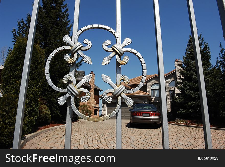 An iron gate as entrance for a mansion in an rich neighborhood. An iron gate as entrance for a mansion in an rich neighborhood.