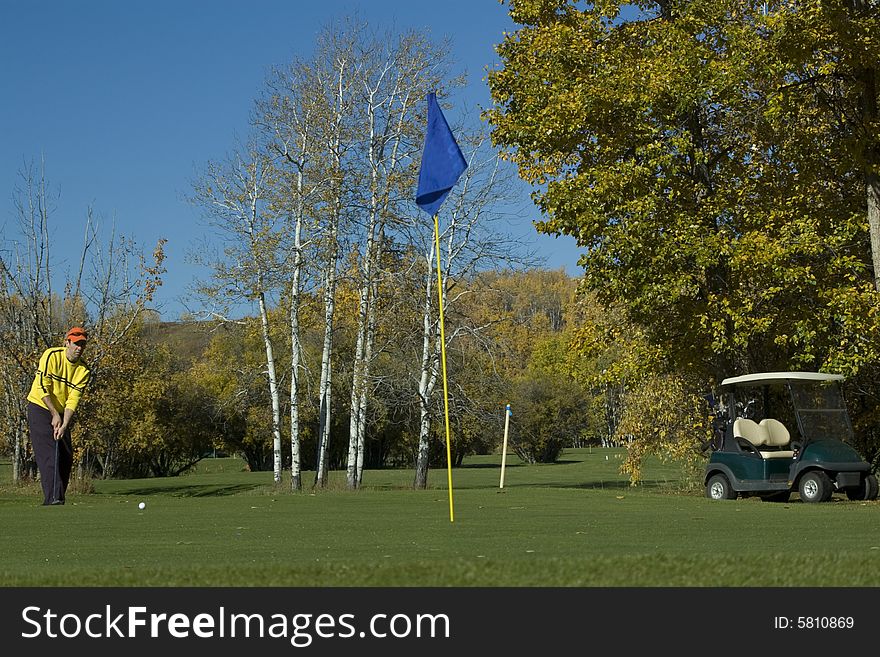 Man putting golf ball towards hole final game of season. Man putting golf ball towards hole final game of season