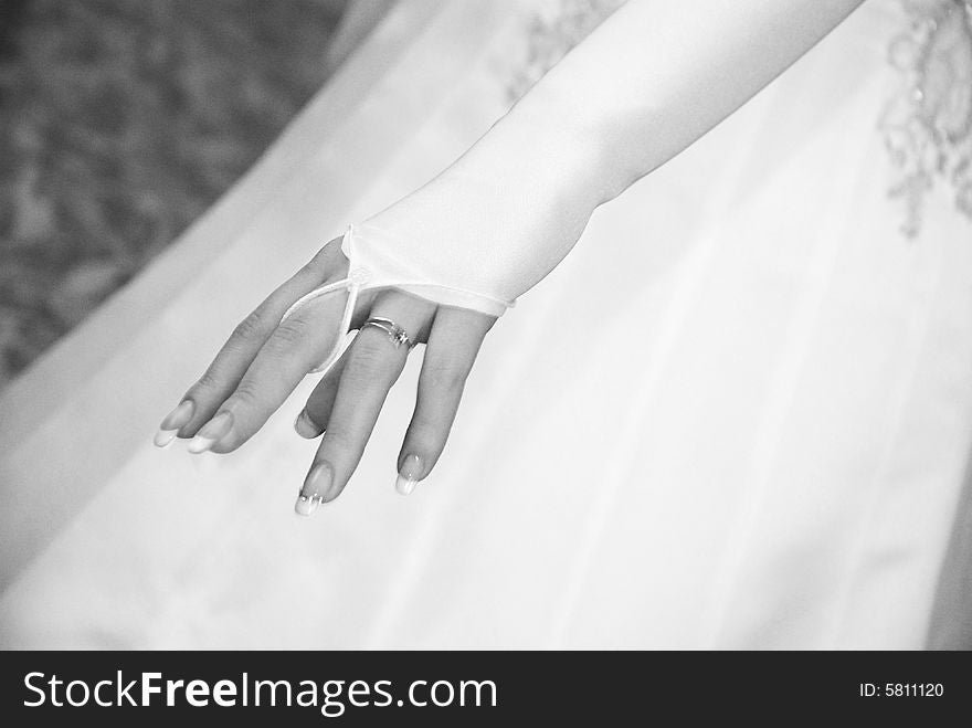 Hand of fiancee in white clothes with a wedding ring on a finger
