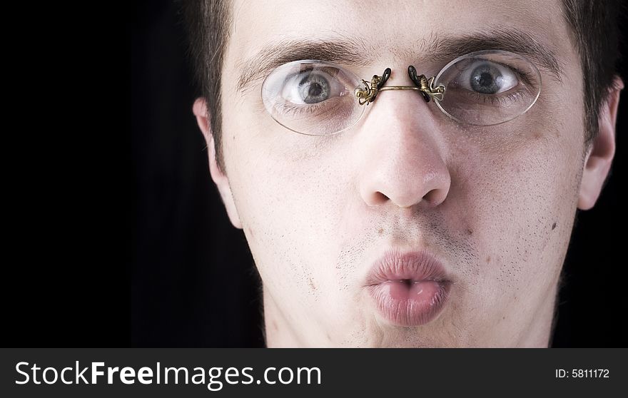 Surprised face of young man in glasses on a black background