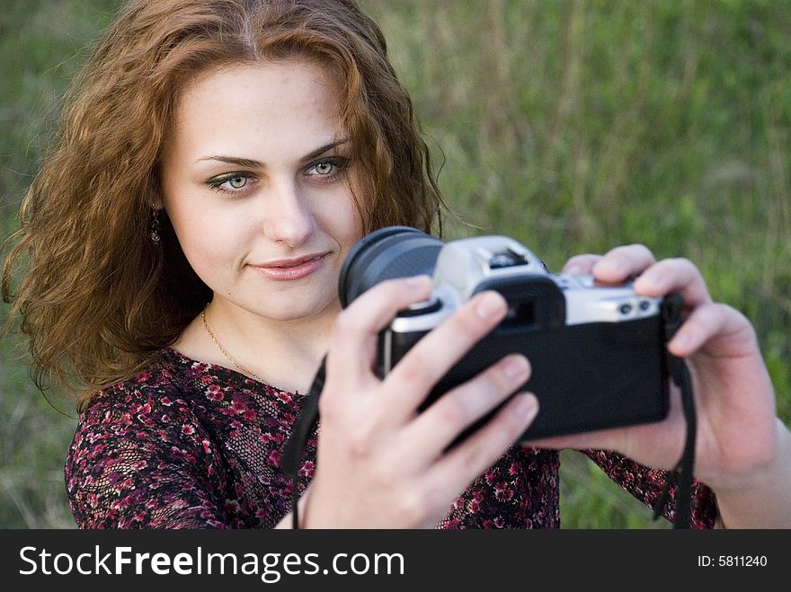 Young attractive girl, gets on the hip a camera and, enigmatically smiling, looks in a shot. Young attractive girl, gets on the hip a camera and, enigmatically smiling, looks in a shot