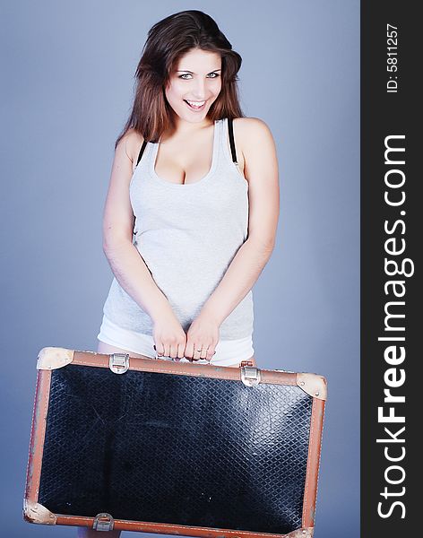 A girl in a grey shirt with beautiful hair holds a suitcase in a hand. A girl in a grey shirt with beautiful hair holds a suitcase in a hand
