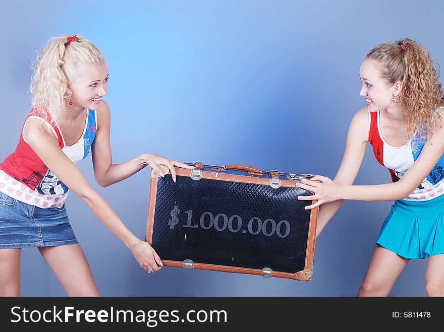 Two young beautiful girls are dressed in identical shirts hold an old suitcase. Two young beautiful girls are dressed in identical shirts hold an old suitcase