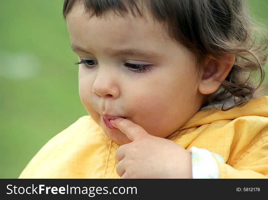 Little girl in deep thoughts put her finger in the mouth. Little girl in deep thoughts put her finger in the mouth