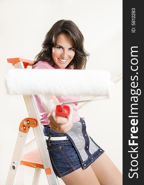 Young woman holding paint roller and smiling. Young woman holding paint roller and smiling