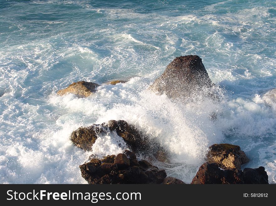 Waves breaking on the rocks in the blue ocean