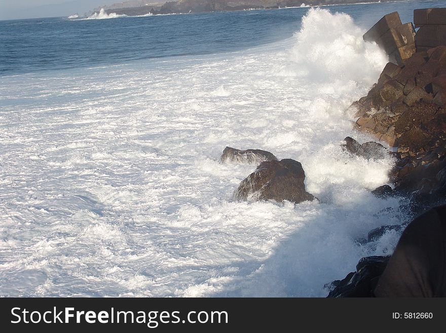 Waves breaking on the rocks in the blue ocean