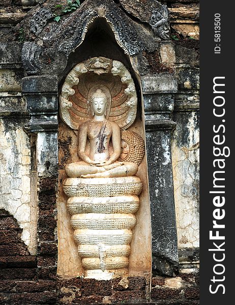 Thailand, Sri Satchanalai historical park; Detail of a carved wall with a seated Buddha protected by the seven head Khmer naga. Thailand, Sri Satchanalai historical park; Detail of a carved wall with a seated Buddha protected by the seven head Khmer naga