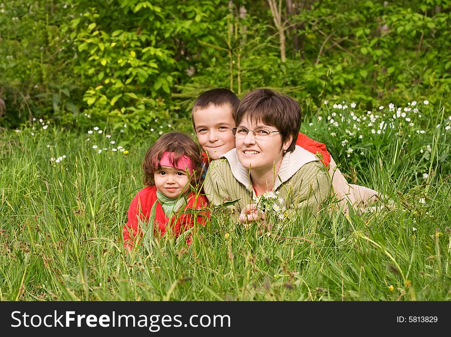 Woman and her kids laying in the spring grass. Woman and her kids laying in the spring grass