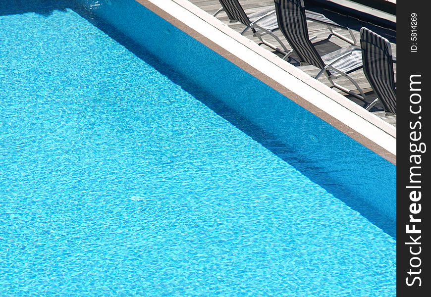 A pool with blue water and some decks chair in the solarium. A pool with blue water and some decks chair in the solarium