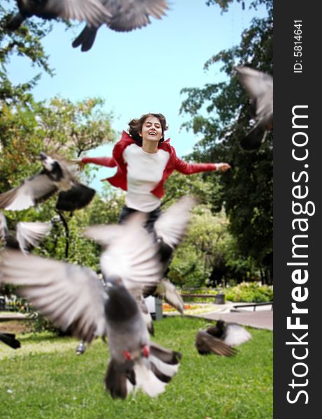Smiling woman in a park, chazing pigeons with scattered hands
