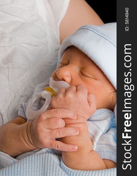 Newborn baby boy holds his pacifier in while taking a nap. Newborn baby boy holds his pacifier in while taking a nap