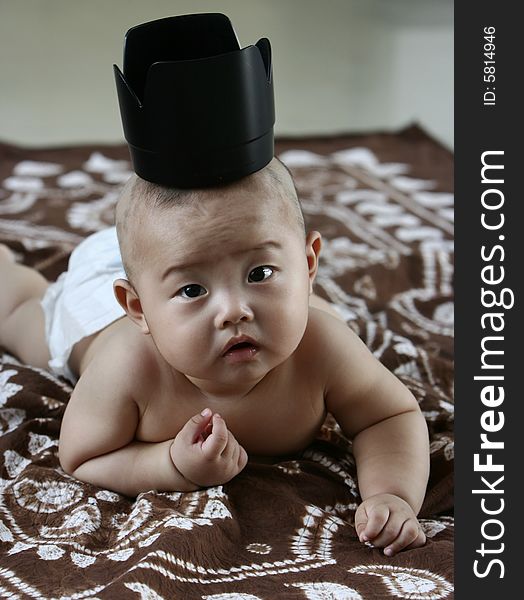 Chinese baby boy with a lens hood as his crown