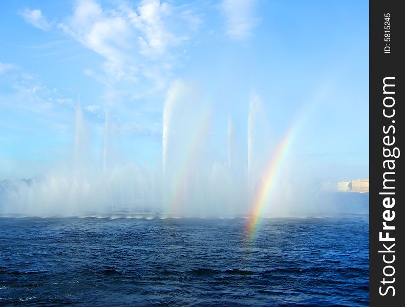 Photo of a fountain on the river with a rainbow.