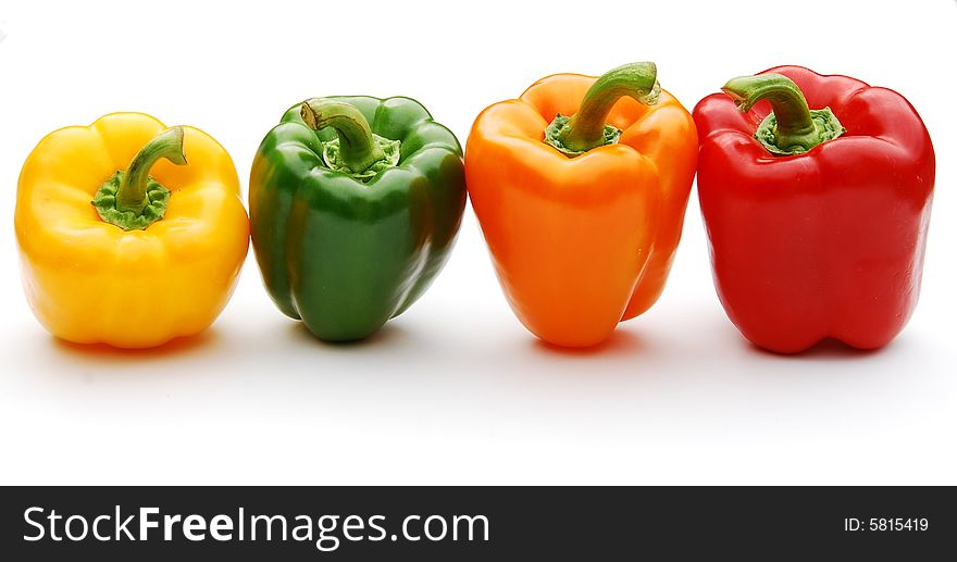 Shot of a four differnt coloured peppers in a row isolated on white