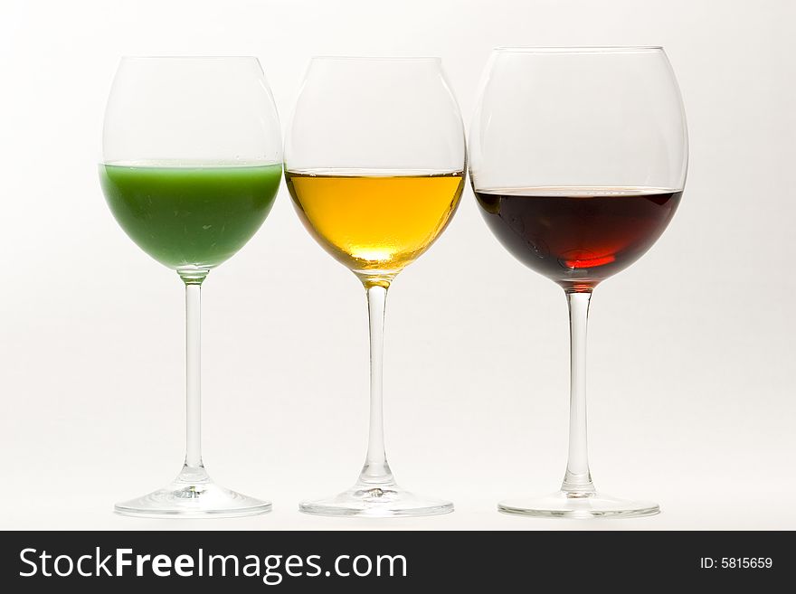 Three tall glasses on white background filled with: white, red wine and green cocktail