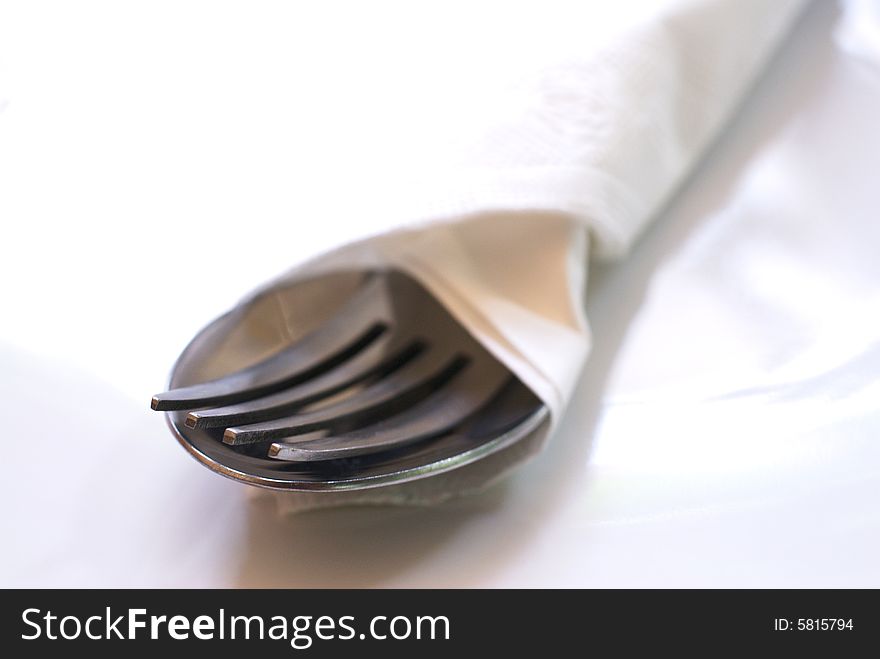Cutlery wrapped in a napkin and placed elegantly on a white plate. Cutlery wrapped in a napkin and placed elegantly on a white plate.