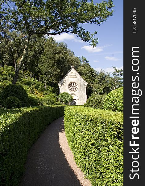 Curved pathway through neat hedges to a small stone church. Curved pathway through neat hedges to a small stone church