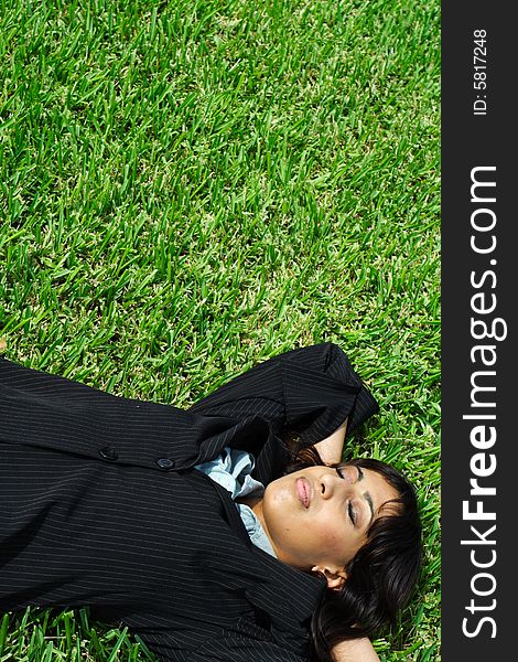 Businesswoman taking a nap on a field of plush green grass. Businesswoman taking a nap on a field of plush green grass.