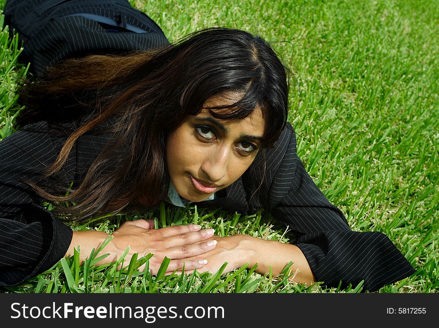 Businesswoman taking a nap on a field of plush green grass. Businesswoman taking a nap on a field of plush green grass.