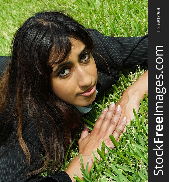 Businesswoman taking a nap on a field of plush green grass. Businesswoman taking a nap on a field of plush green grass.