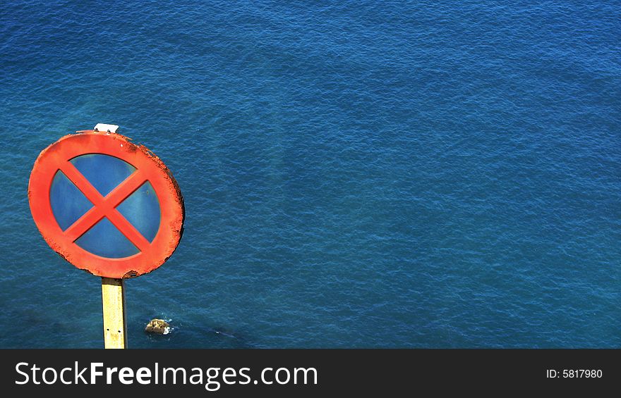 No parking sign post with blue sea in the background